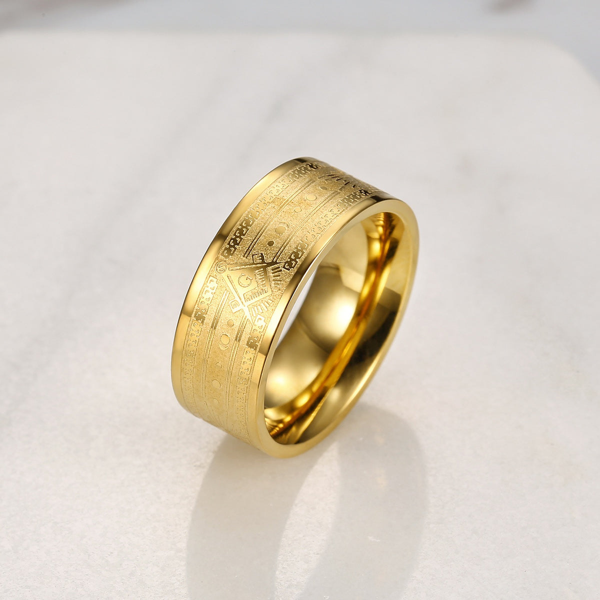 Stainless steel gold Masonic ring resting on a light background